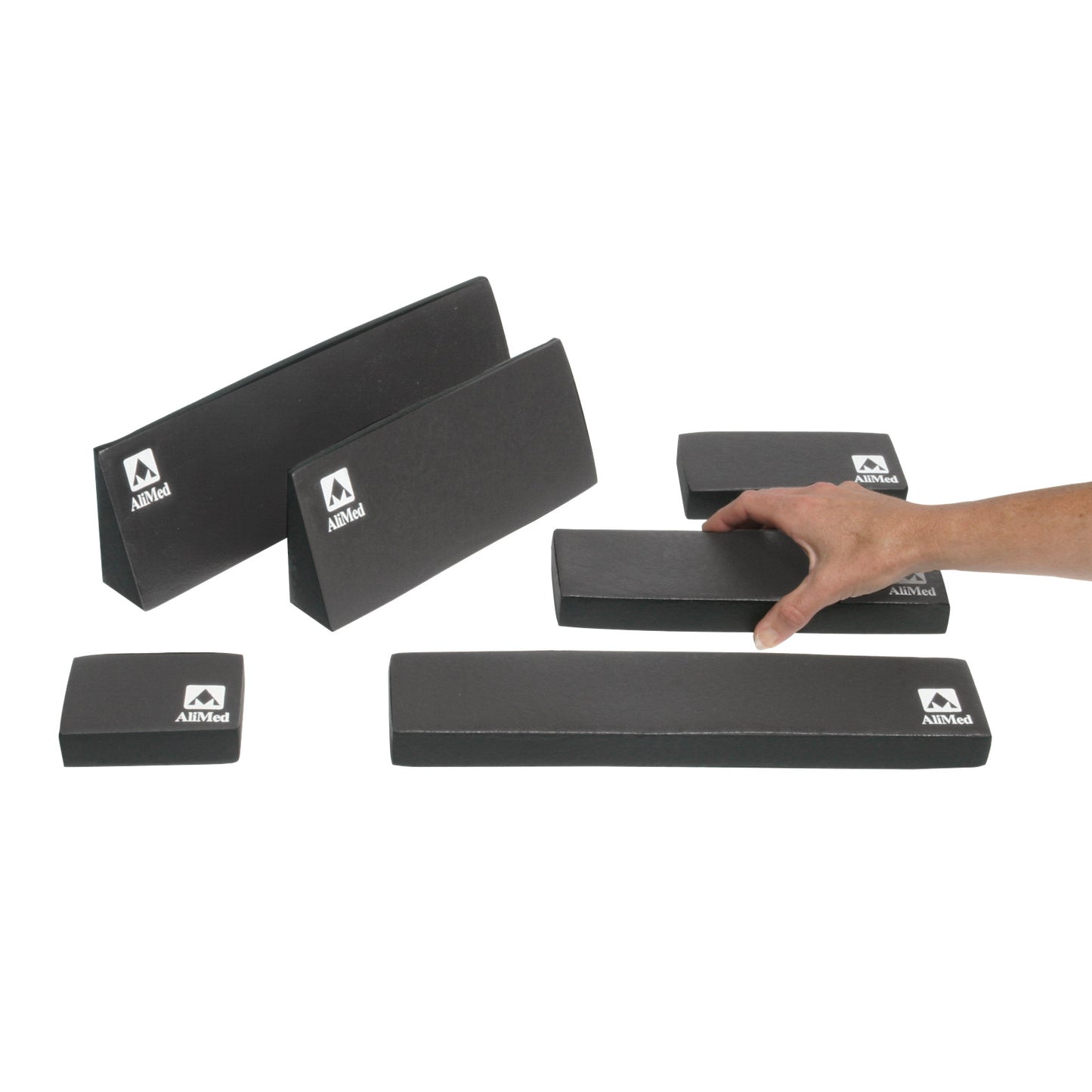 Various sizes of black AliMed MRI Immobilization Positioner blocks are displayed, with a hand selecting one.