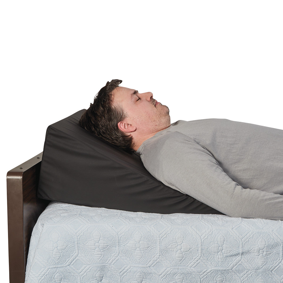 A person lies on the AliMed Bariatric Anti-Reflux Elevating Bed Wedge, covered with a light quilt.