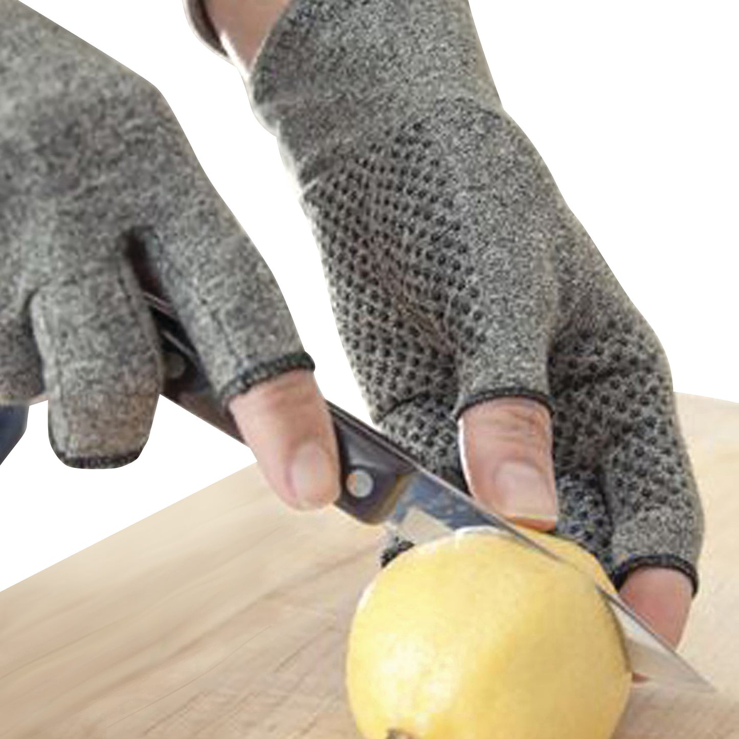 Hands wearing Brownmed IMAK Compression Arthritis Gloves slice a lemon with a knife on a wooden surface.