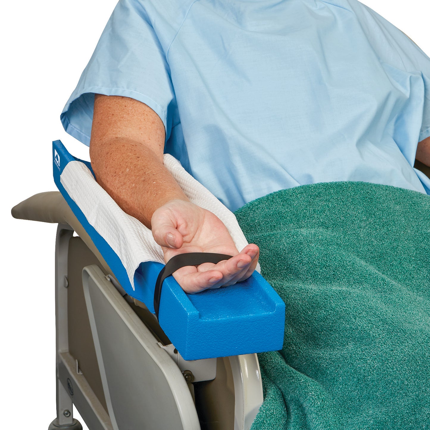 A patient in a blue gown lies on a recliner with an arm secured by the AliMed Dialysis Arm Positioner Kit, covered by a green blanket.