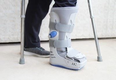 person walking with crutches and ankle boot