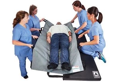 nurses using a patient transfer sheet to transfer patient