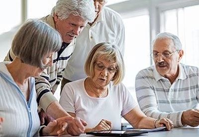 group of people sitting around table looking at tablet