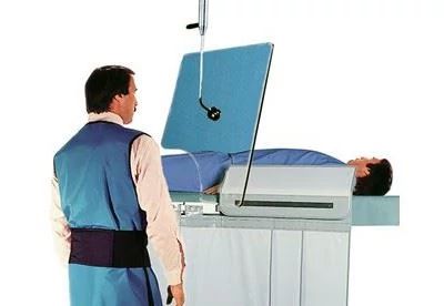 doctor in room with patient on operating table with raidaition shield