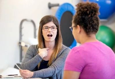 speech therapist showing patient pronunciation with throat