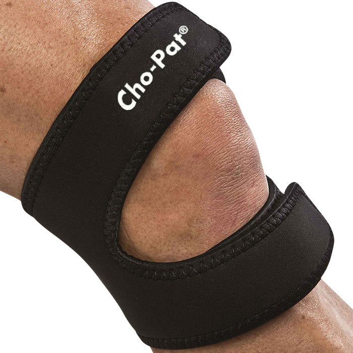 A person wearing a black Cho-Pat Dual-Action Knee Strap, designed for knee support and pain relief.
