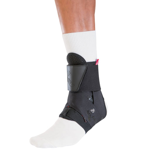 A person wearing a white sock has the Mueller The One Ankle Brace on their right ankle for support and protection.