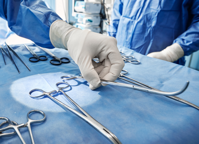 surgeon picking up surgical instruments
