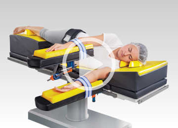 patient on operating table with patient positioners and safety straps with video icon